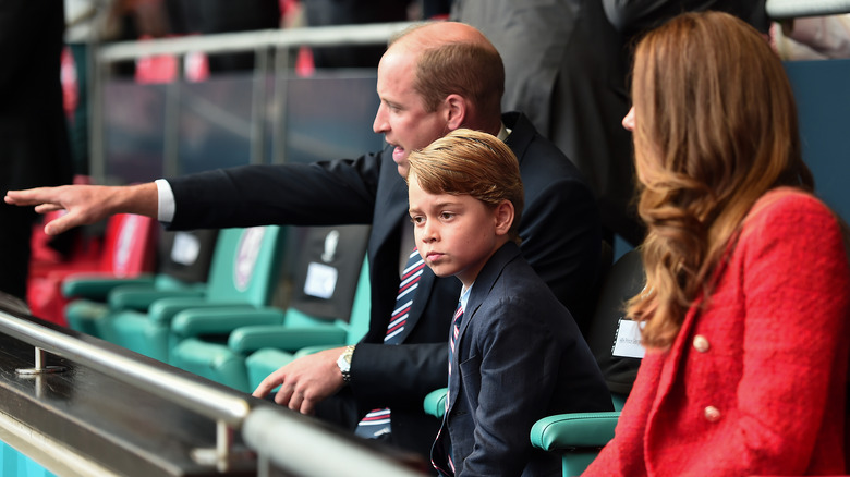 George sitting with his parents in bleachers