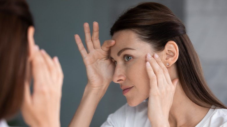 white woman looking at wrinkles in mirror