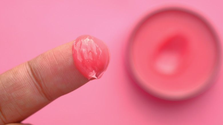 Pink lip gloss tube open and sitting on a pink background