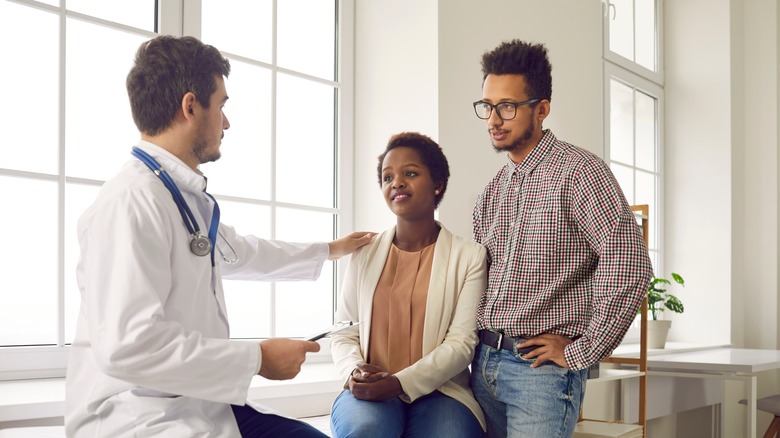 Man and woman talk to a doctor