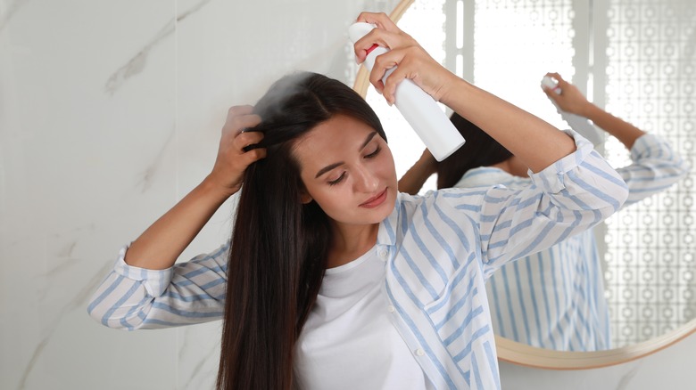 Woman putting dry shampoo on her hair