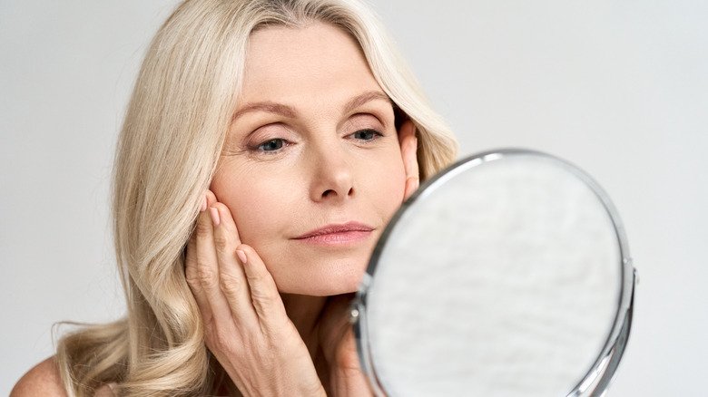 A woman inspecting her face in the mirror 