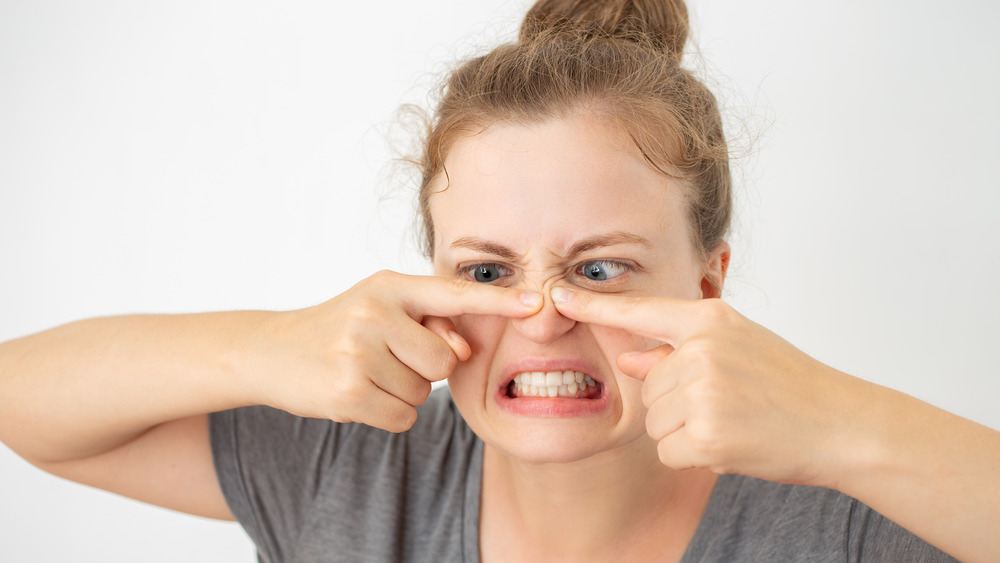 woman squeezing blackheads on nose