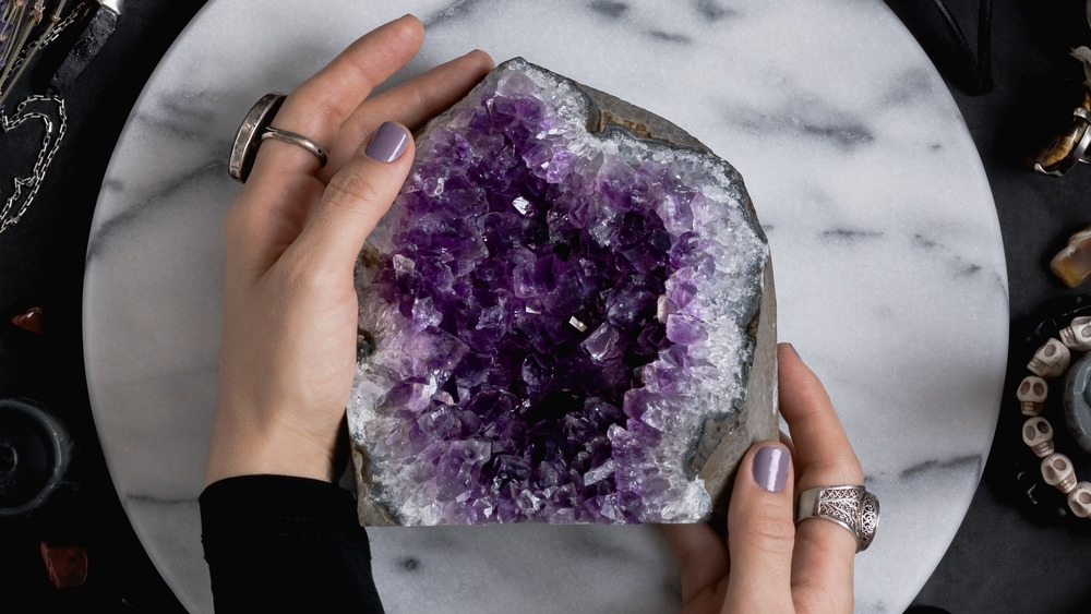 Hands holding an amethyst geode 