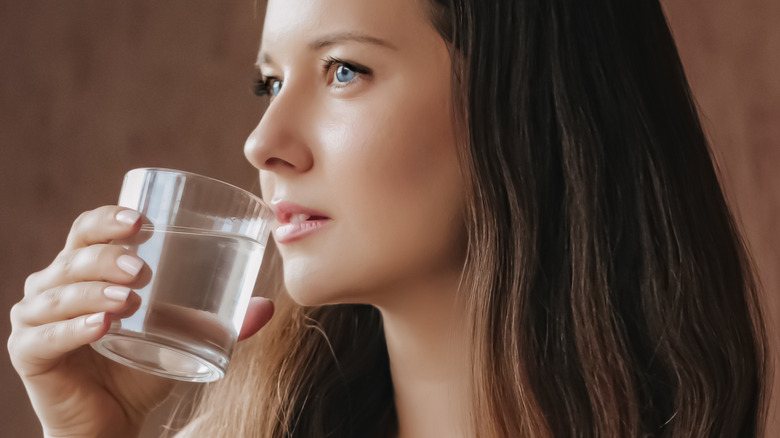 Brunette woman drinking water from a glass.