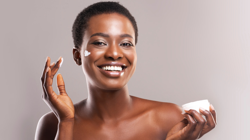 Woman applying moisturizer to face