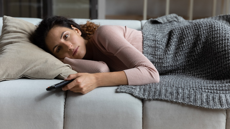 Woman lying on couch, holding remote