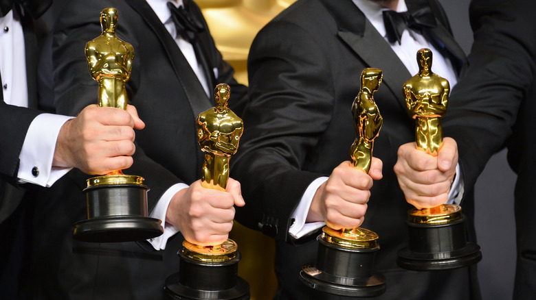 Hands holding Oscars statues