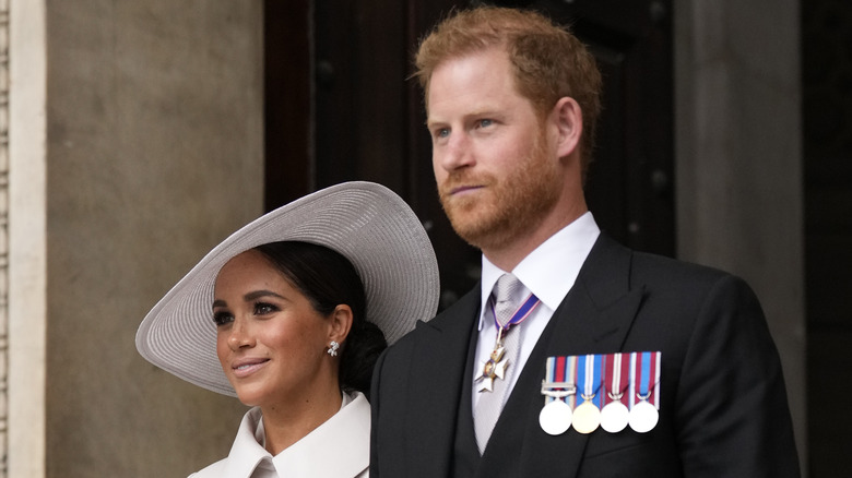 Meghan Markle smiling and Prince Harry looking serious