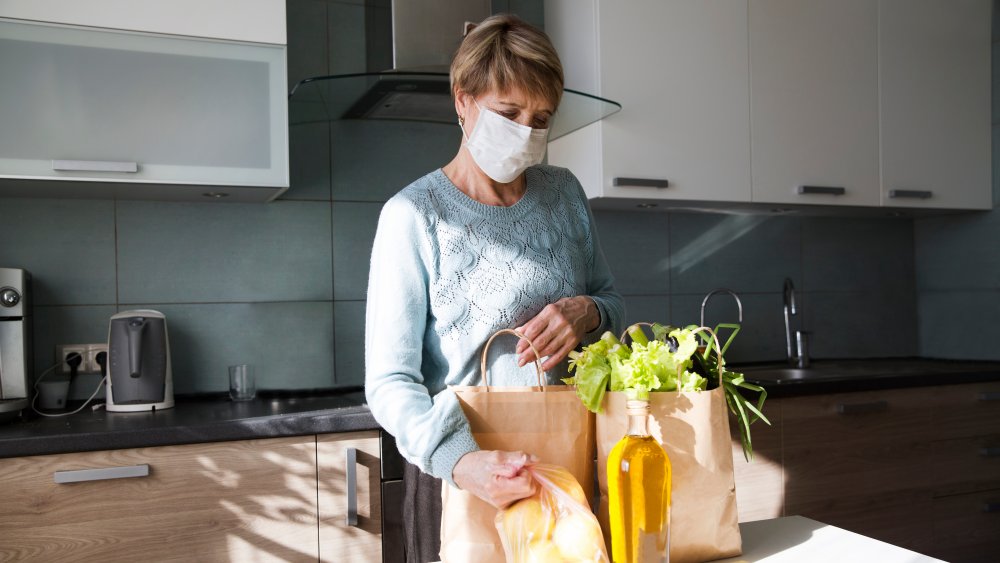 Woman wearing mask unpacking groceries