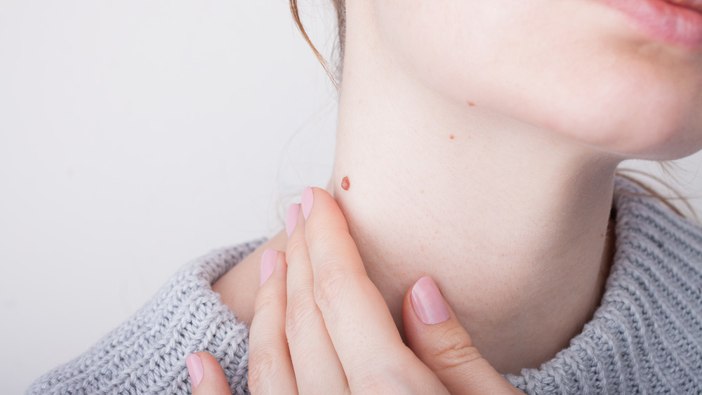 A woman is touching her neck.