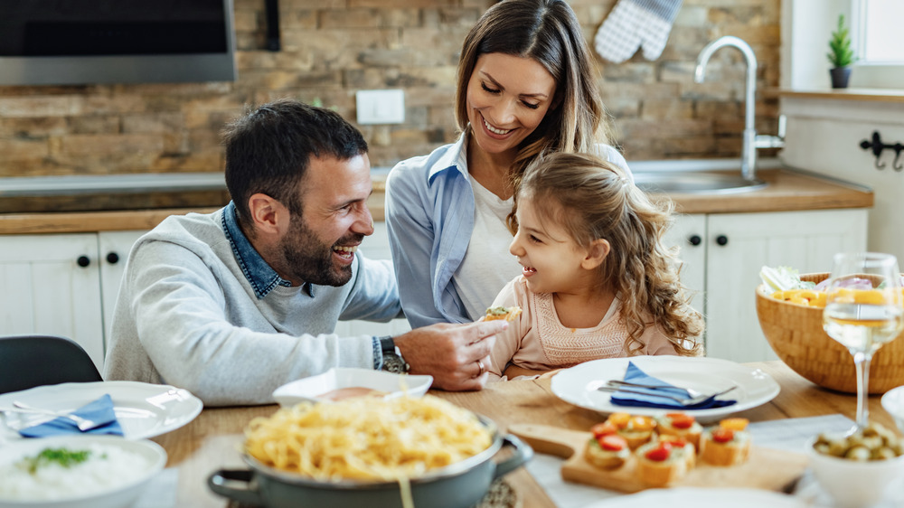 Family smiling while enjoying a meal at home