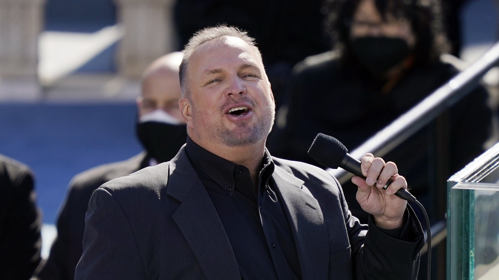 Garth Brooks singing with a smile in black shirt and jacket