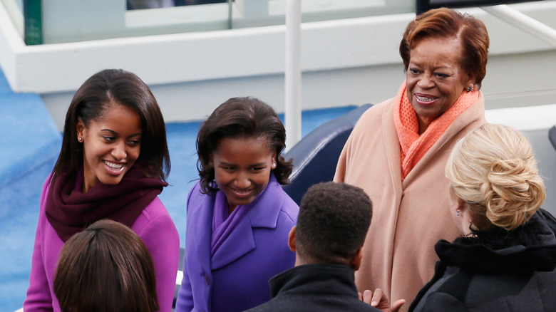 Malia and Sasha Obama and Marian Robinson smiling while greeting people