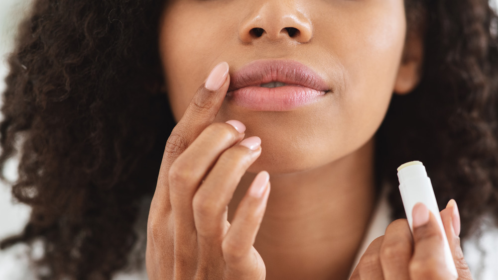 Woman applying nude lip color with her finger 