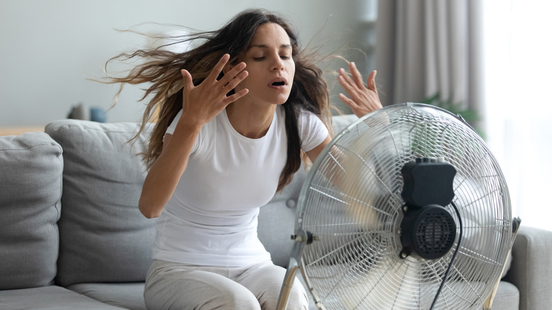 Woman cooling down with fan 