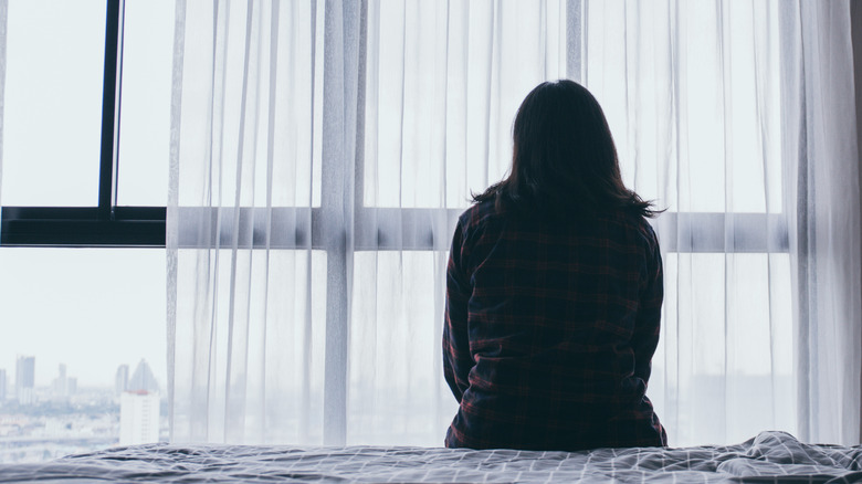 woman sitting on a bed with her back to the camera