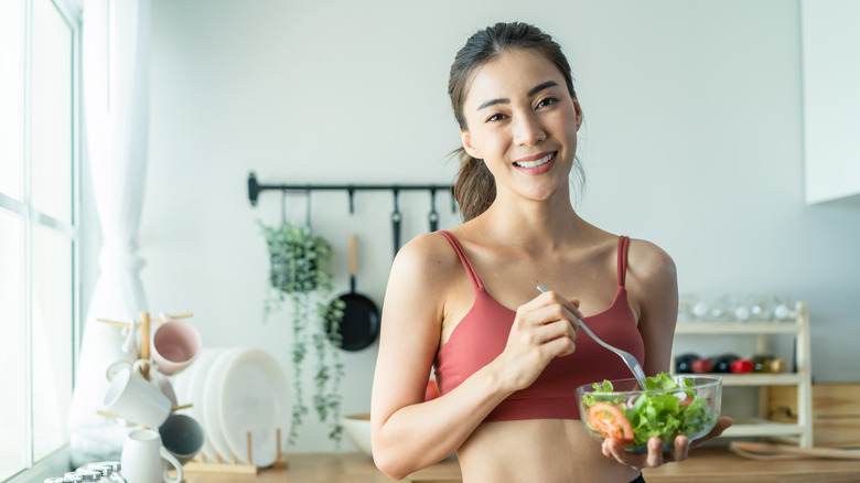 Woman eating salad in kitchen