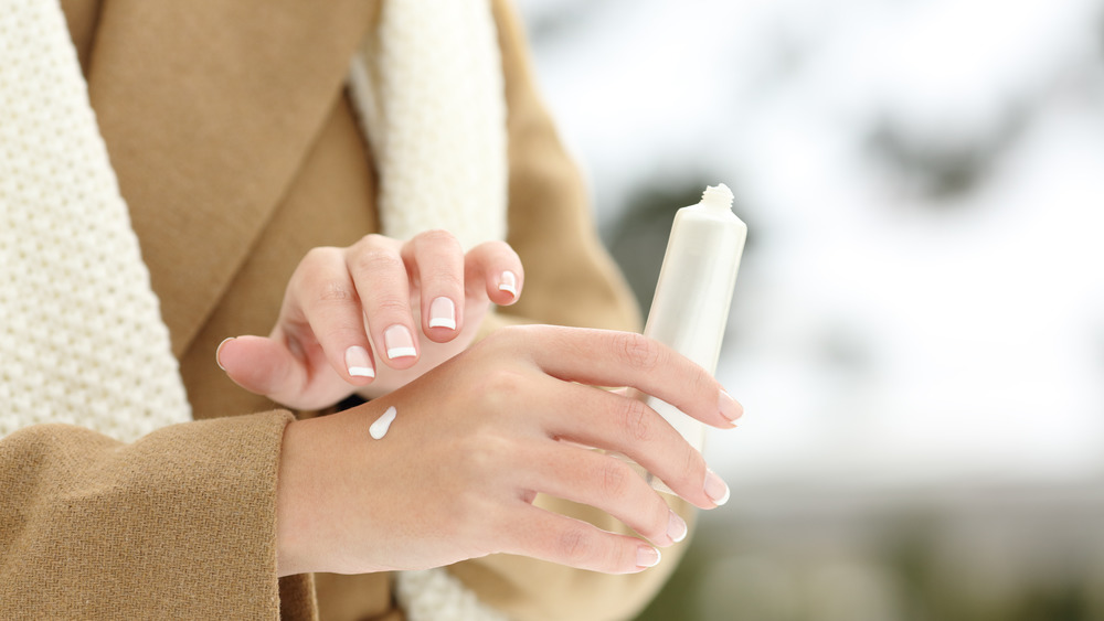 Woman applying moisturizer to her hands during the winter