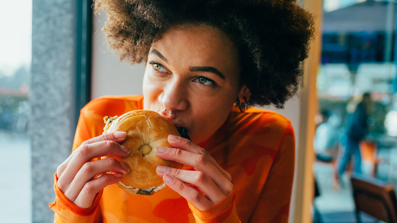 woman eating a bagel sandwich