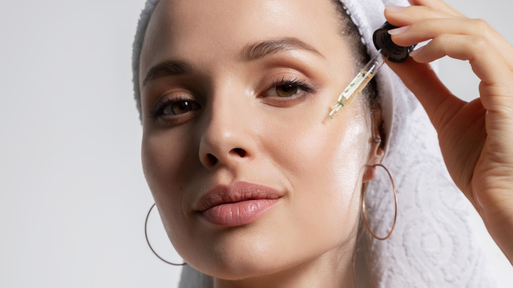 Woman putting serum on face