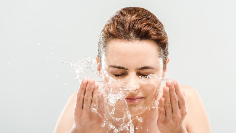 Woman washing face with water