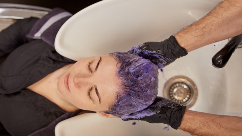 A woman with colored hair getting her hair washed