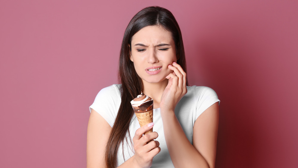 A woman experiencing tooth pain when eating ice cream 