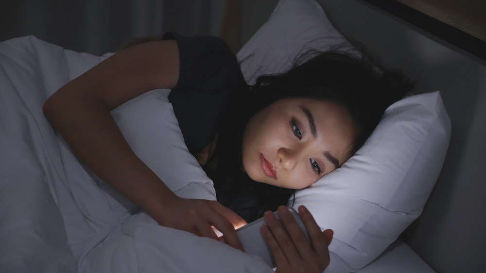 Woman looking at her phone in bed