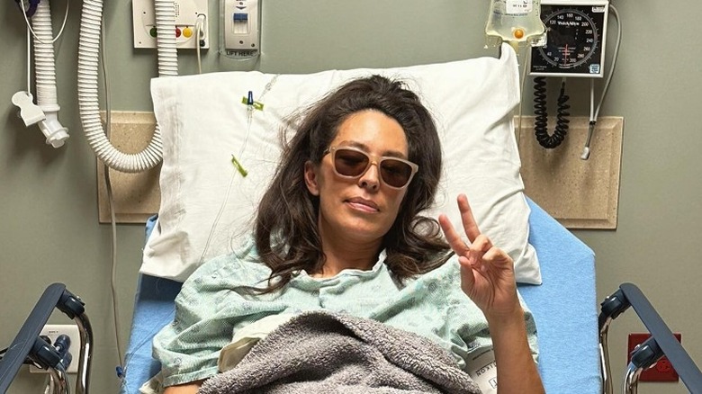 Joanna Gaines in hospital bed giving peace sign