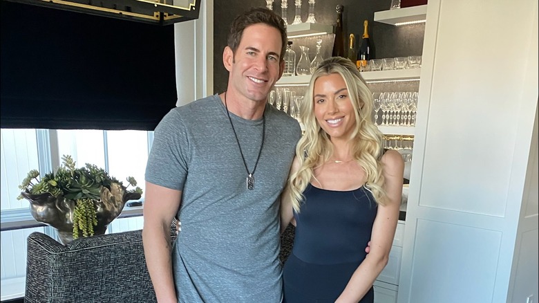 Tarek El Moussa and Heather Rae Young smiling in front of their home bar