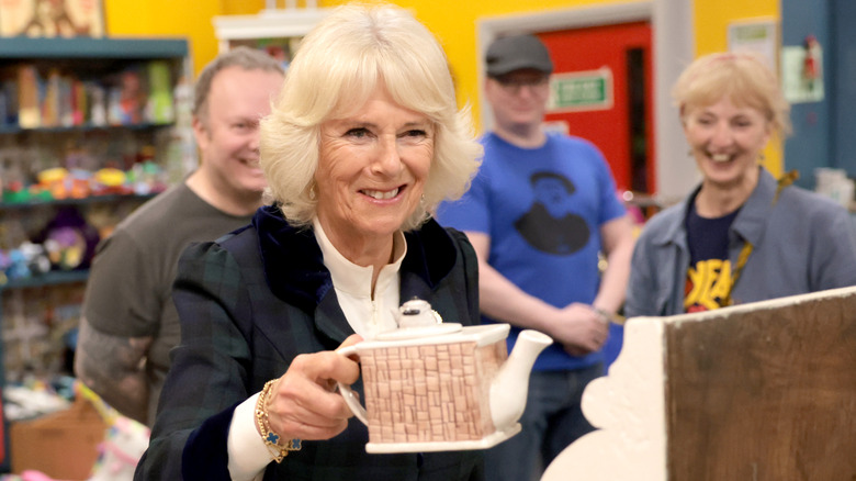 Camilla Parker Bowles holding teapot at Emmaus