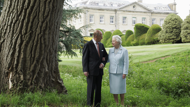 Queen Elizabeth and Prince Philip standing on a lawn