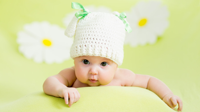 baby with hat and daisies in background