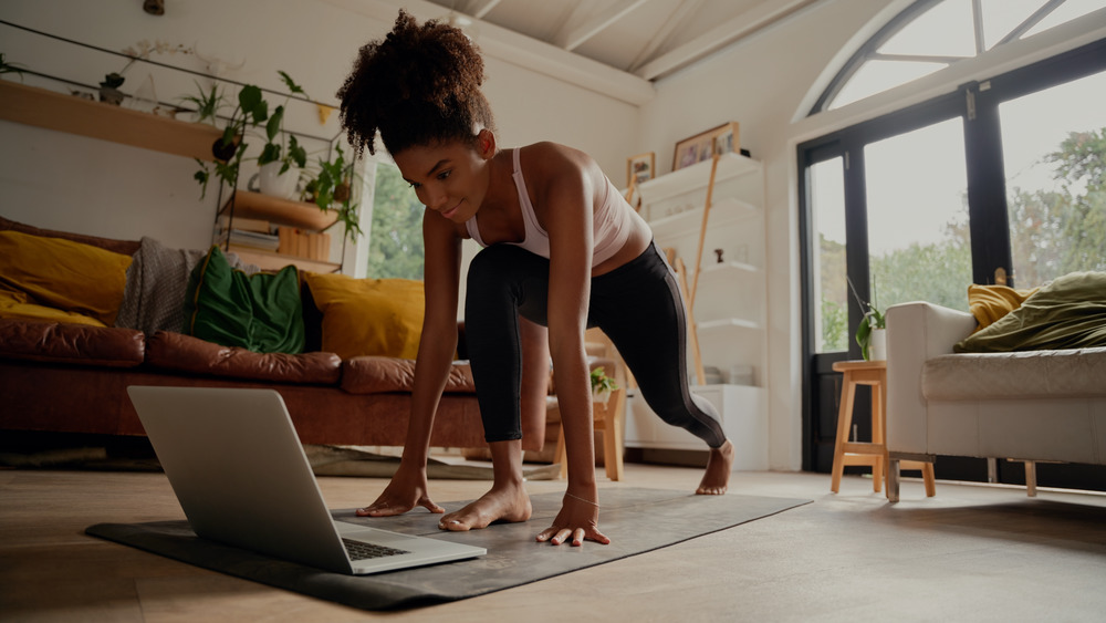 Woman exercising in front of laptop on yoga mat