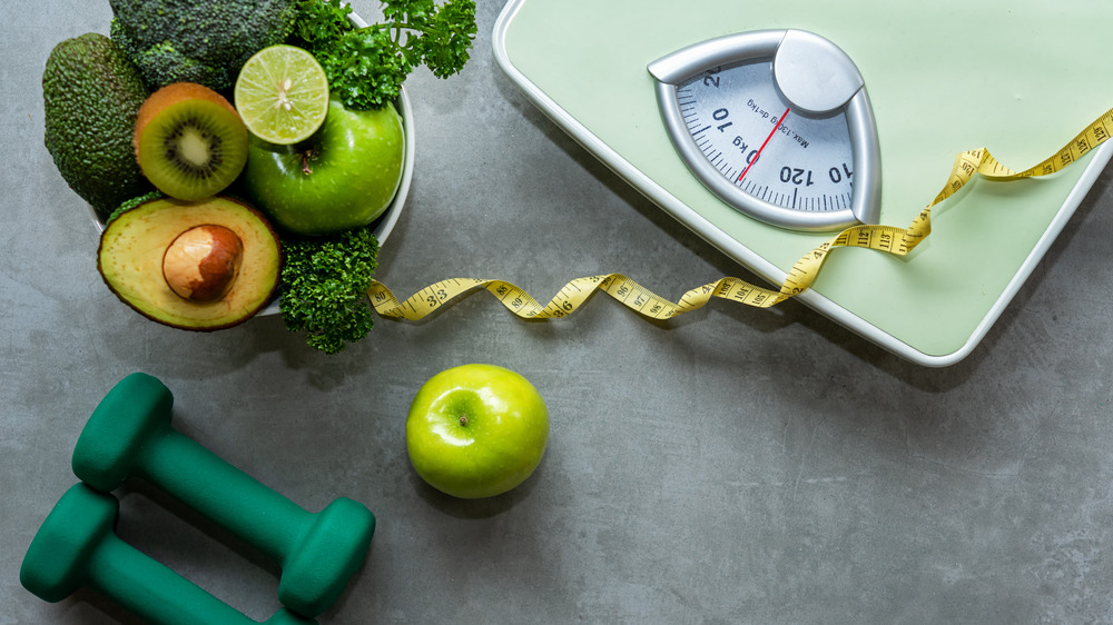 Bowl of fruit and vegetables next to a scale with weights and tape measure