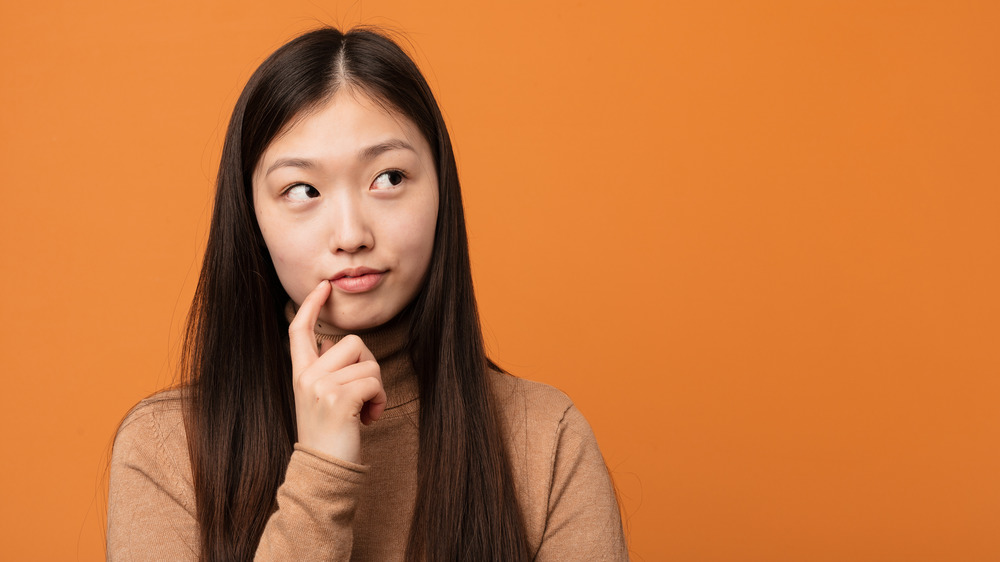 Young woman thinking with finger at lip