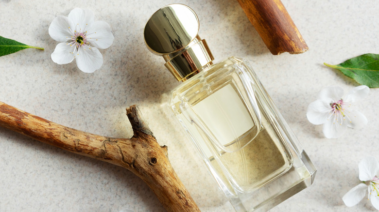 perfume bottle beside flowers and twigs