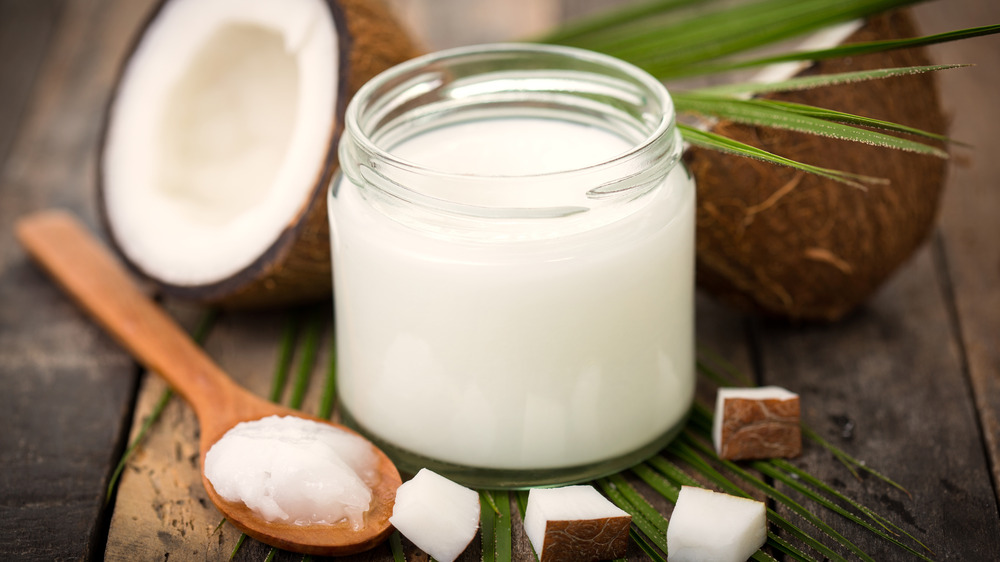 Coconut oil in a jar and on a wooden spoon 