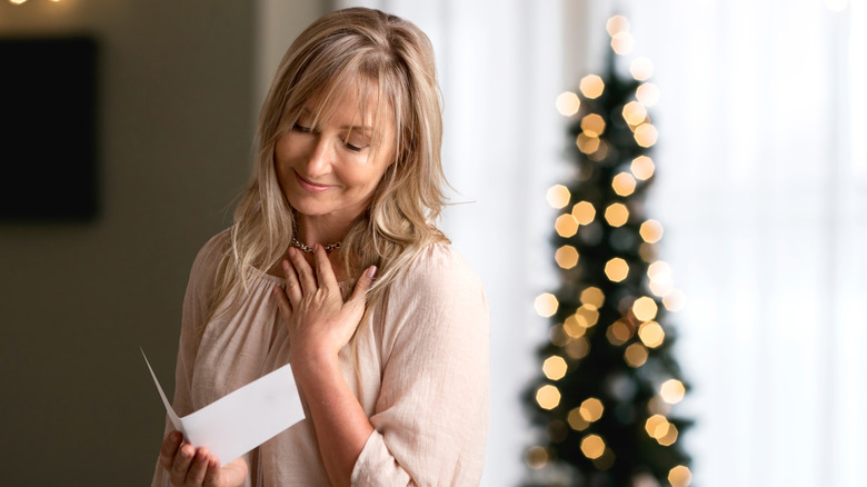 A woman reading a note at Christmas. 