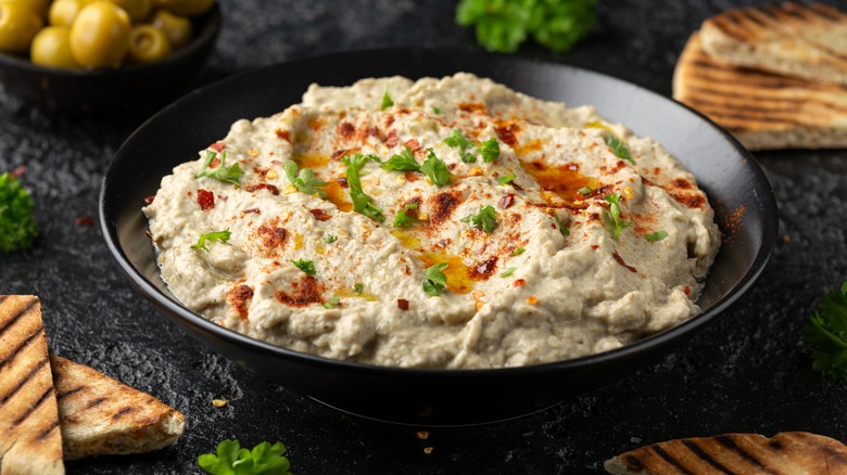 Bowl of hummus with pitas on the side