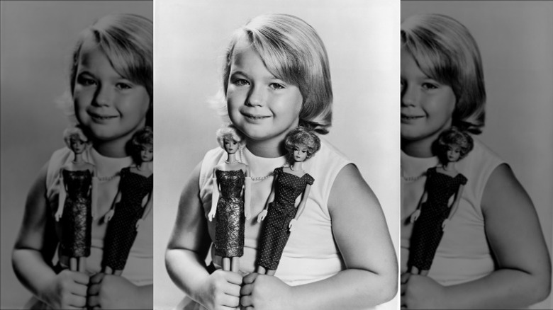 Girl holds two Barbies with bubble cuts