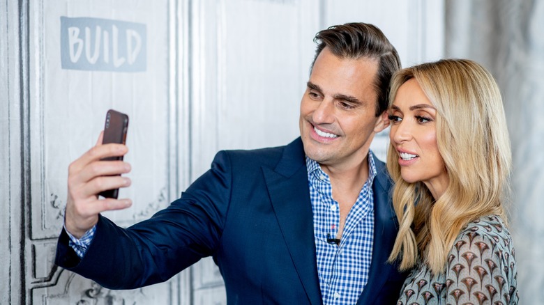 Bill and Giuliana Rancic looking at a phone in 2018