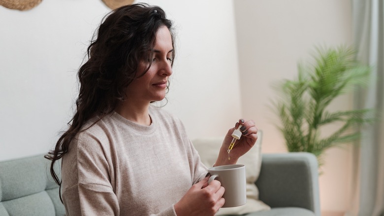 Woman adding CBD oil to a cup of tea