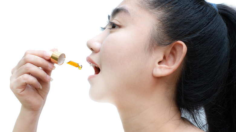 Woman about to ingest dropperful of CBD oil