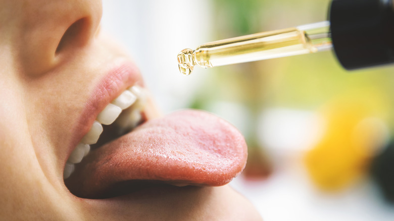 woman taking CBD oil in mouth