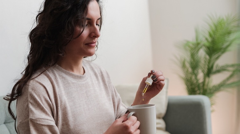 woman dropping CBD into drink