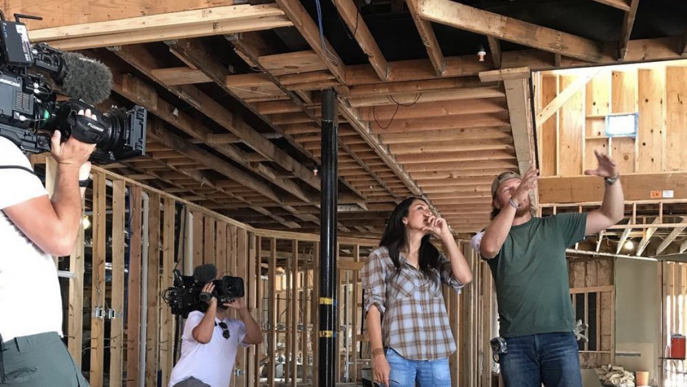 Fixer Upper's Chip Gaines and Joanna Gaines being filmed by camera operators