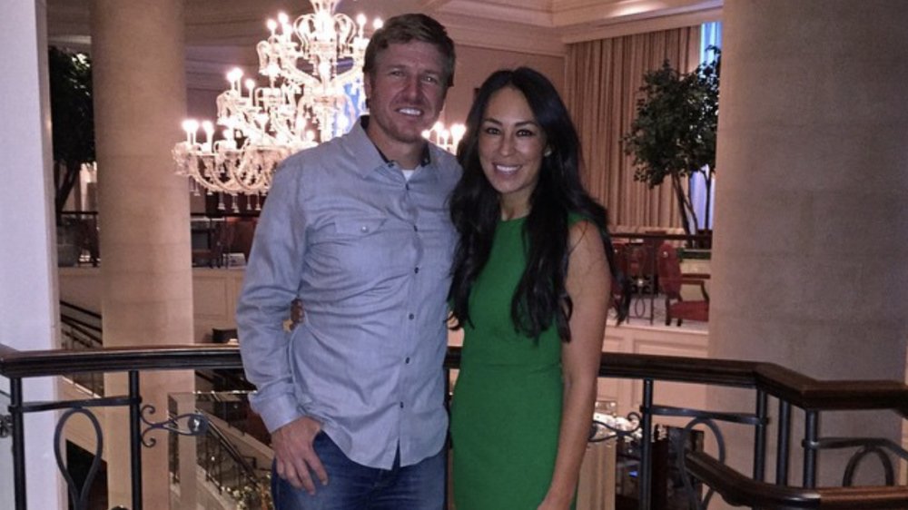 Fixer Upper's Chip Gaines and Joanna Gaines in front of a chandelier