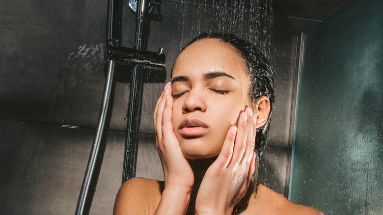 Woman washing face in cold shower